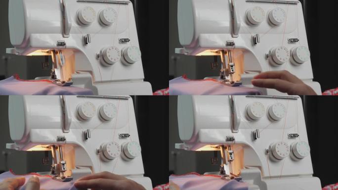 在缝纫机上覆盖织物边缘的特写。女人的手握着布料，缝着衣服，特写着。包锁机的细节。创造和剪裁服装。时尚