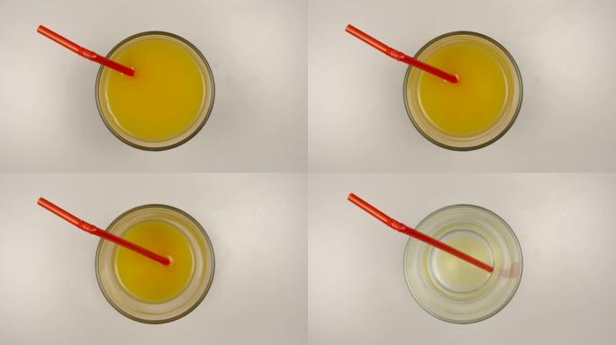 顶视图: 用吸管从玻璃停止运动中饮用新鲜的橙汁