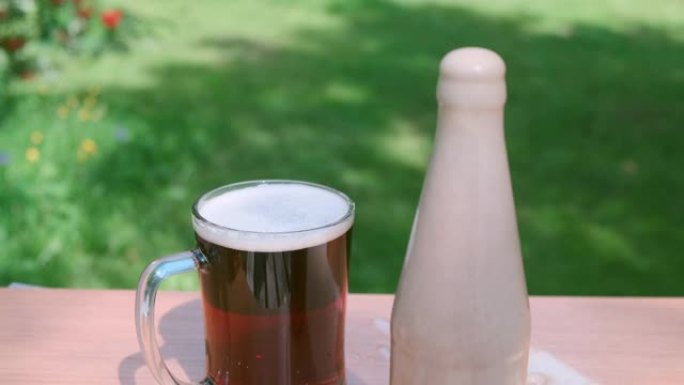 带瓶的新鲜黑啤酒，绿色花园中的泡沫。夏天的时候。