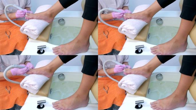 修脚的女人使用电动钉甲机从客户的脚趾上去除角质层。