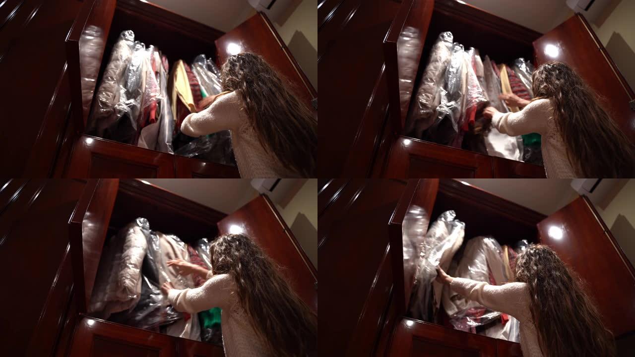 黑发女孩在她的木制衣柜里翻找，女人在衣架上选择衣服，决定穿什么。家里的衣柜，选择问题概念