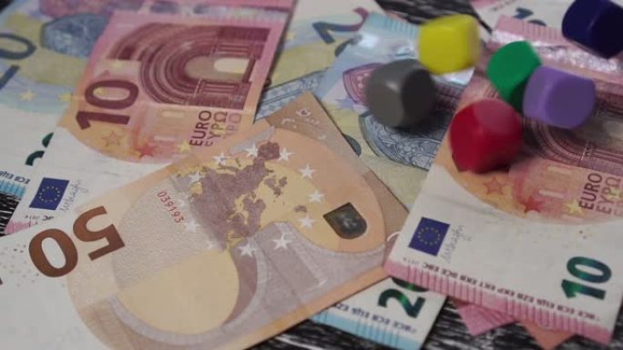 在一堆欧元纸币上，6个多色骰子掉落