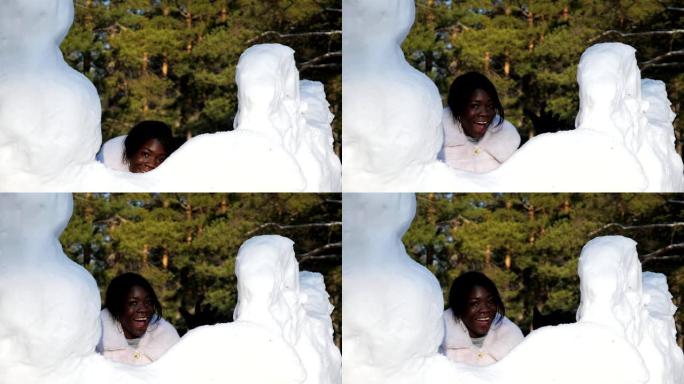 黑皮肤的女孩躲在雪堆后面玩得开心