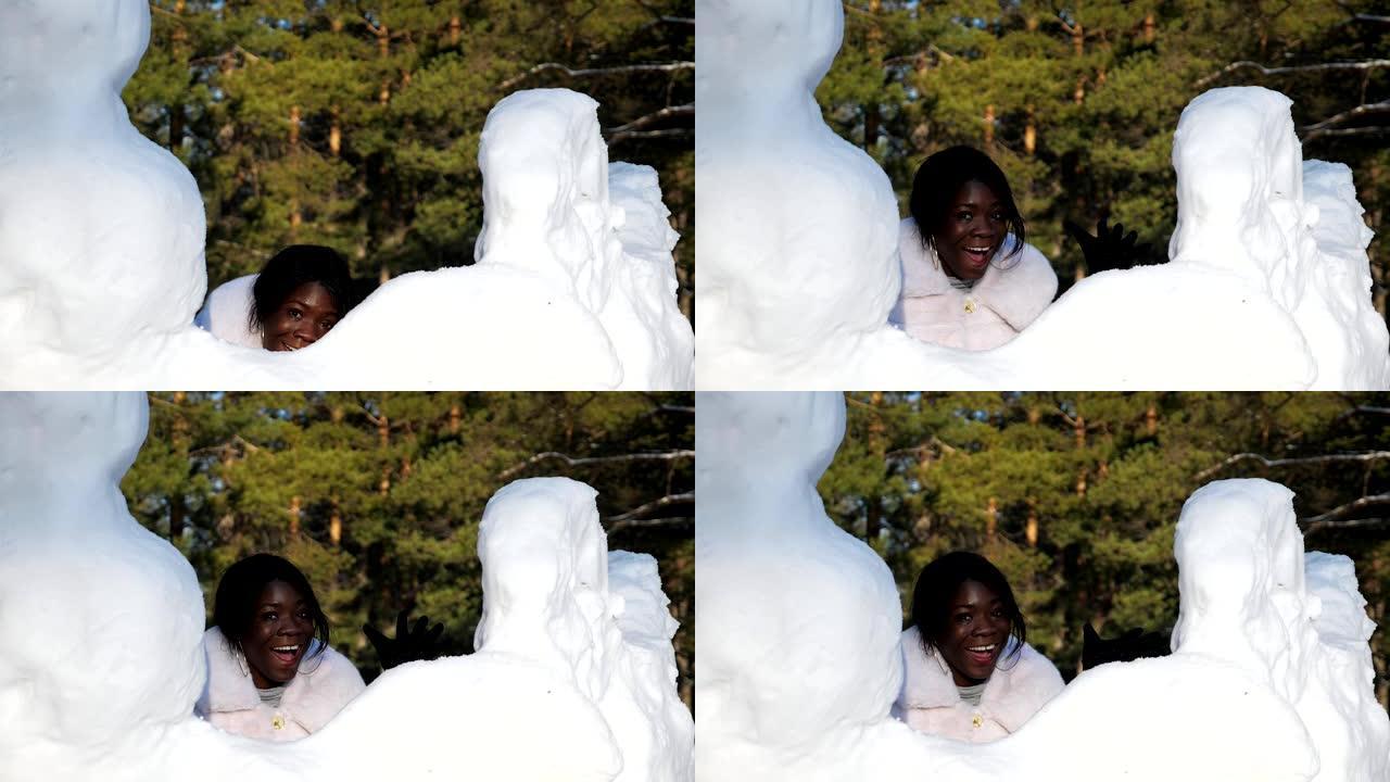 黑皮肤的女孩躲在雪堆后面玩得开心