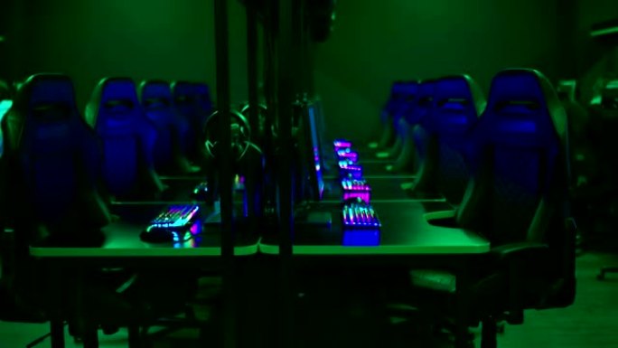 配备设备和计算机的现代网络俱乐部。桌子和椅子排成一排，电脑俱乐部的黑暗房间。
