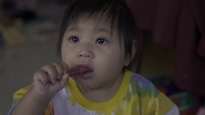 幼儿园快乐的小宝贝女孩正在用彩色铅笔吃饭。