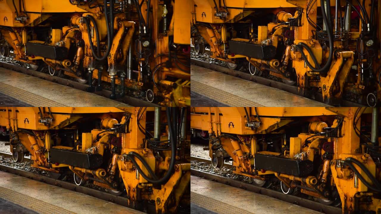 发动机机器在火车站的铁路上以金属钢动力在火车行业的步道上移动。黄色机器轨道轨道工业机械轨道，用于向列