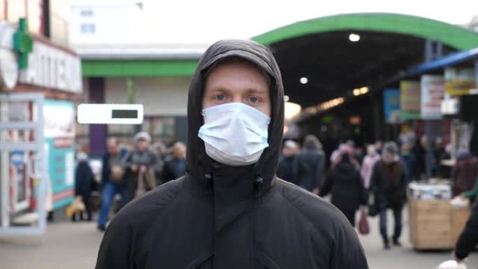 戴着医用口罩的年轻人的肖像站在城市街道上。一个人戴着防护面具从病毒户外的人群拥挤。冠状病毒和流行病的