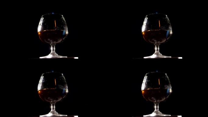 干邑玻璃的特写镜头，干邑在黑色背景上缓慢旋转。