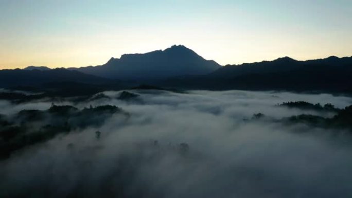 婆罗洲沙巴雾蒙蒙的雨林丛林中以基纳巴卢山为背景的美丽日出的空中4k镜头