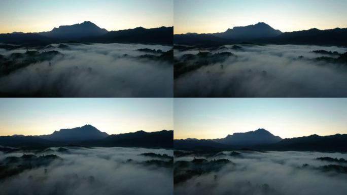 婆罗洲沙巴雾蒙蒙的雨林丛林中以基纳巴卢山为背景的美丽日出的空中4k镜头