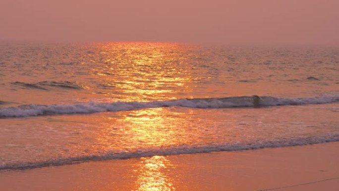 日落时分的阳光在潮湿的沙滩和即将到来的海浪上的海滩风景
