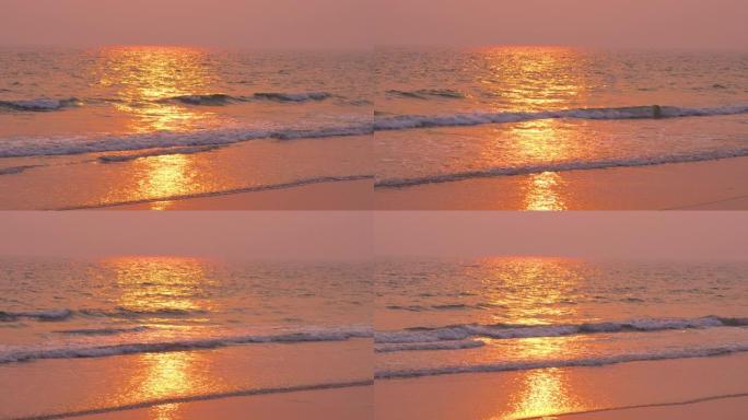日落时分的阳光在潮湿的沙滩和即将到来的海浪上的海滩风景