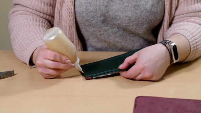 女性双手在皮革钱包零件上涂胶