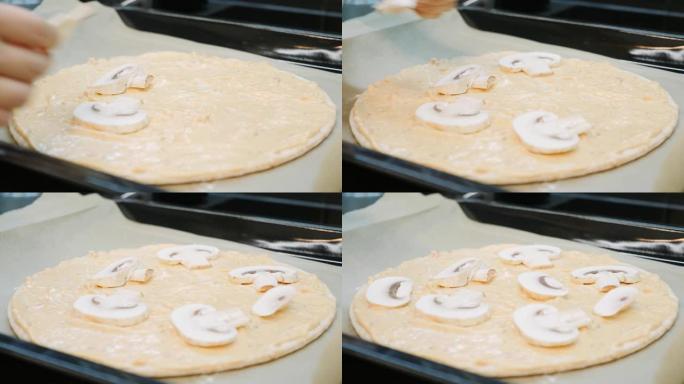 双手将蘑菇添加到比萨饼面团中。女人在厨房准备披萨，特写。厨师在披萨中添加食材