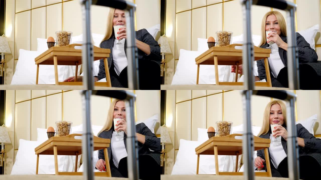 假日旅游生活方式和商业理念。年轻漂亮女人在酒店房间用餐，通过手提箱把手看着相机的肖像。女商人在重要的