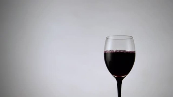 白色背景上红酒杯的平移视图。淡淡的背景下充满酒精饮料的酒杯