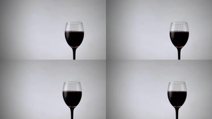 白色背景上红酒杯的平移视图。淡淡的背景下充满酒精饮料的酒杯