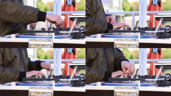 DJ播放音乐，在露天派对上在转盘上刮擦黑胶唱片。双手特写。