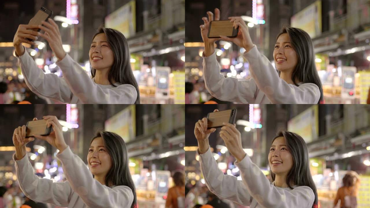 快乐年轻的亚洲女性在夜市使用智能手机