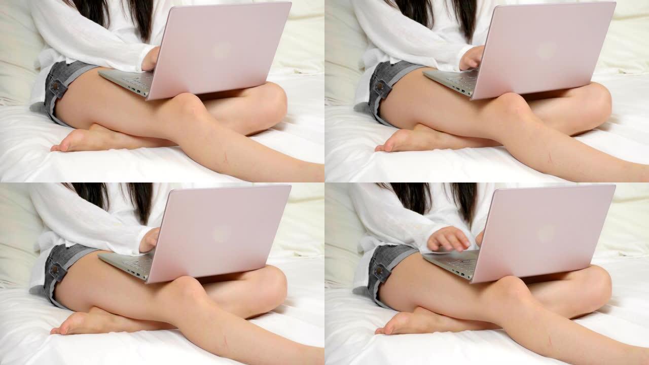 女人坐在雪白的床上用笔记本电脑工作，顶视图