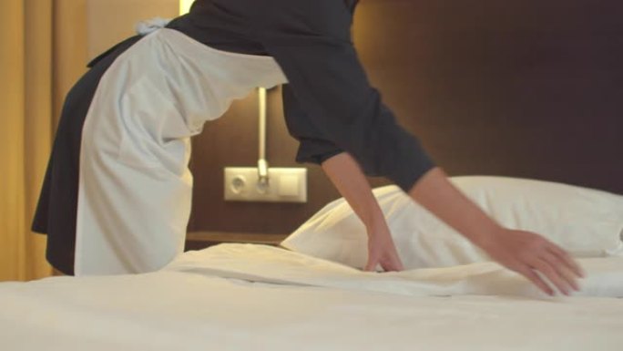 女佣在酒店房间铺床铺毯子