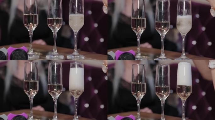 女孩用麦克风将香槟倒入桌子上的玻璃杯中