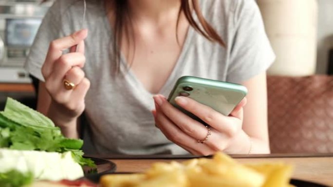 年轻的亚洲女性在餐厅吃早餐时拿着智能手机。