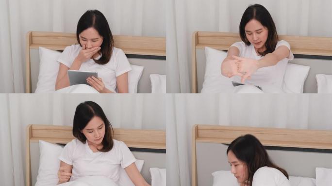 美丽的亚洲女人在床上使用平板电脑，打哈欠看起来很困，然后躺在白色床上