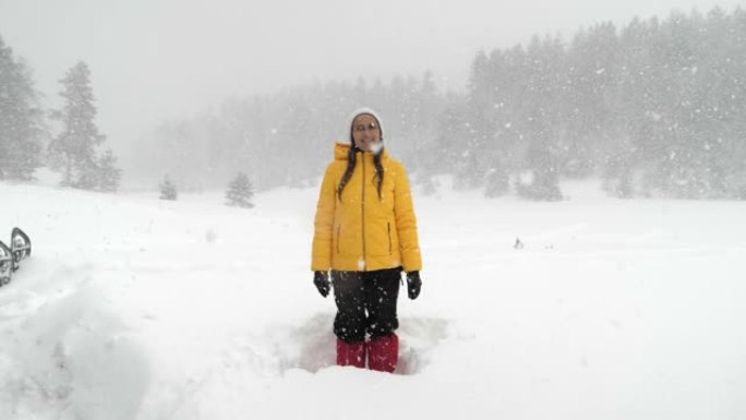 冬季旅行者。一位年轻女性游客的慢动作，在深雪中享受外面的降雪。在冬天的山上玩得开心。肖像。