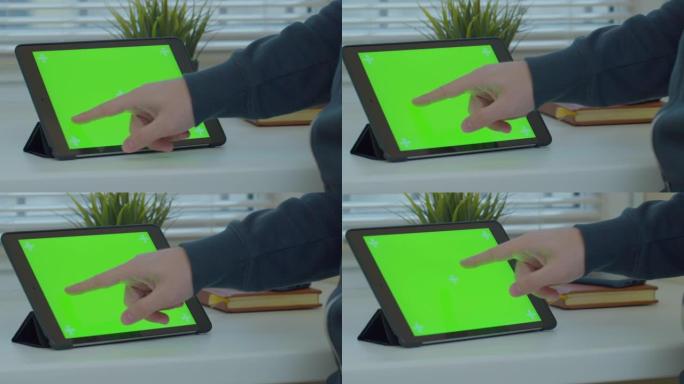 男人使用带有绿屏的平板电脑在线上网。关闭chromakey屏幕。