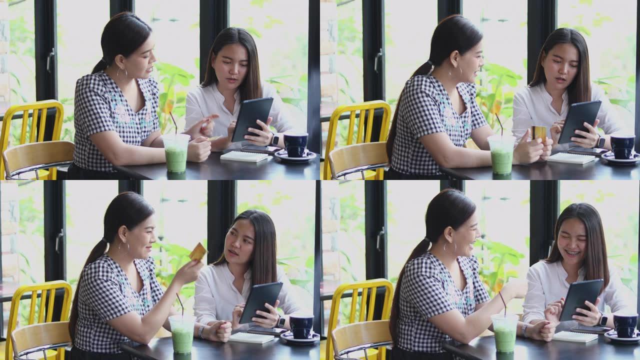 两名亚洲妇女在咖啡馆喝咖啡，并在智能手机上在线购物