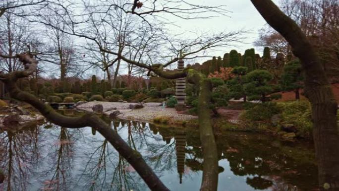 在日本花园里用镜面水拍摄池塘的平底锅，河岸上安装了传统的日本灯笼