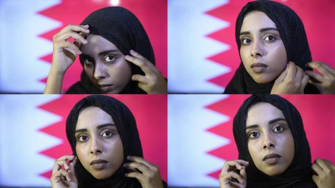 特写年轻美丽的穆斯林女孩戴着头巾，站在卡塔尔国旗上