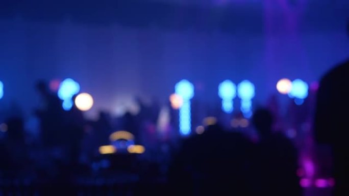 在音乐会或迪斯科舞厅，在夜总会的舞池里，在五颜六色的聚光灯下，人们在桌子上走着和坐在桌子上的模糊轮廓