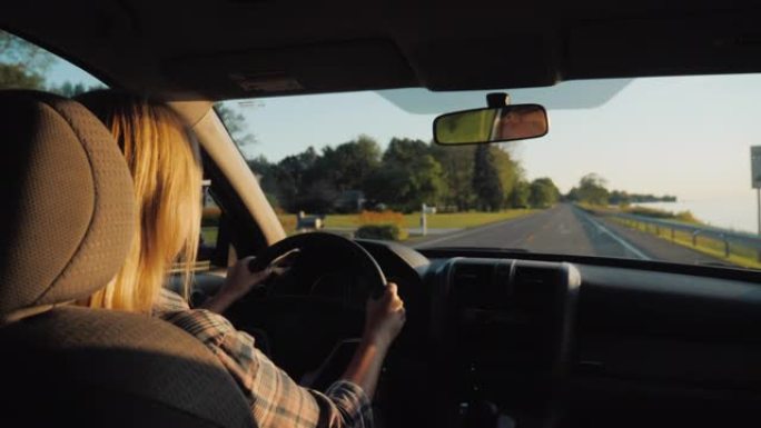 在美国郊区驾驶汽车的迷人中年妇女的后视图