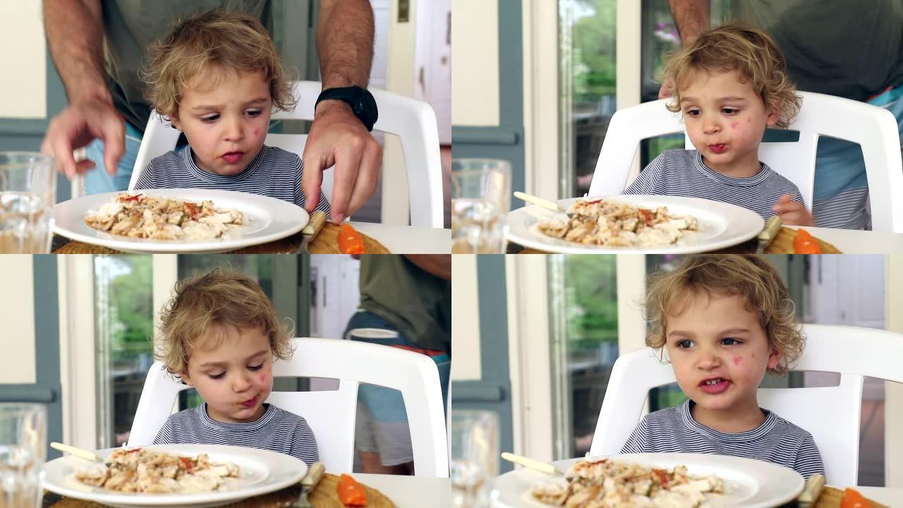 午餐桌上的小男孩即将吃父亲调整儿子的坦率和现实生活