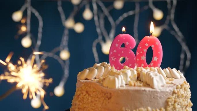 生日蛋糕，蓝色背景上有60个粉色蜡烛和烟火。慢动作和特写视图