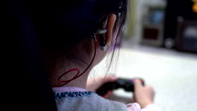 用操纵杆玩电子游戏的小女孩。专注于助听器。