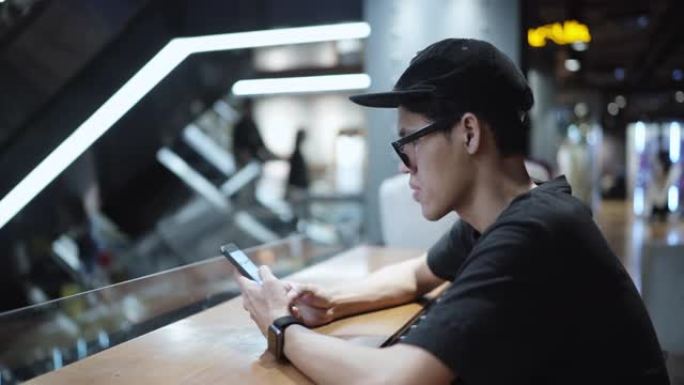 亚洲男子在午夜咖啡馆使用智能手机