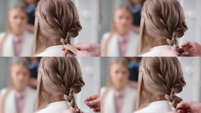 女理发师在金色长发上编辫子后视图特写。用4K红色相机拍摄