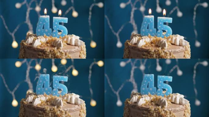 蓝色背景上有45号蜡烛的生日蛋糕。蜡烛吹灭了。慢动作和特写视图