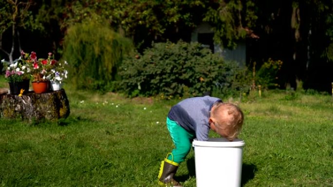 两岁男孩在花园里玩水。湿孩子在自己身上泼水