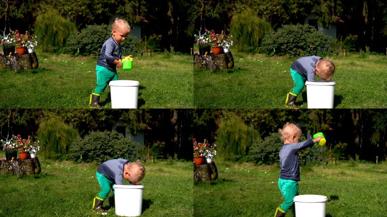 两岁男孩在花园里玩水。湿孩子在自己身上泼水