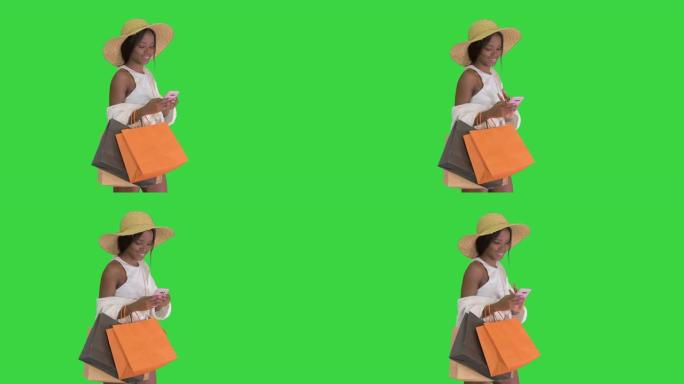 穿着夏装的女人使用手机在绿色屏幕上行走，色键