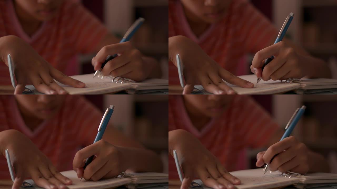 一个小女孩在笔记本上写字的特写手。女学生在日记上做笔记。用写作材料做作业。
