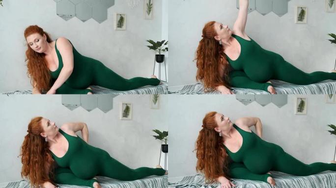 孕妇在卧室练习瑜伽。红发母亲练习瑜伽