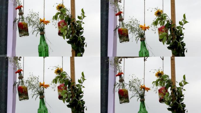 挂在空中的瓶子里的植物和鲜花。