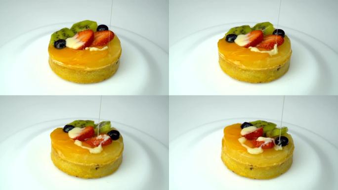 将蛋糕与蓝莓，猕猴桃，橙子，草莓一起倒在盘子上旋转。