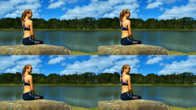 顶部的金发女孩坐在石头上看着湖边的景色